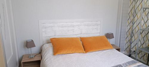- une chambre avec un lit et deux oreillers orange dans l'établissement Appartement T2, à Argelès-Gazost