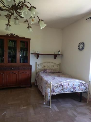 PancoleにあるCasale In Maremmaのベッドルーム1室(ベッド1台付)、木製キャビネットが備わります。