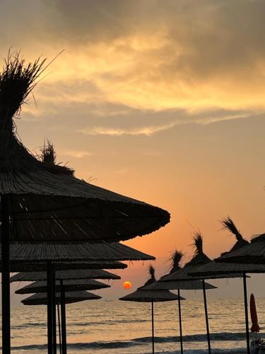 a group of straw umbrellas on the beach at sunset at Holiday apartment, Qerret in Golem