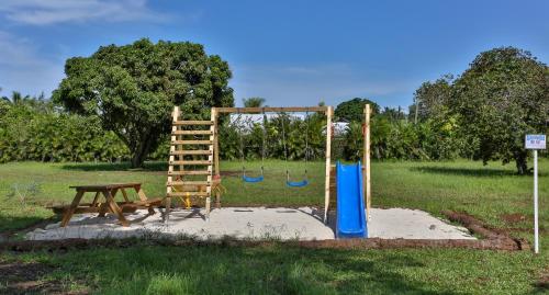 un parque infantil con banco y columpio en Sublime Tahiti Beach Retreat, en Mataiea
