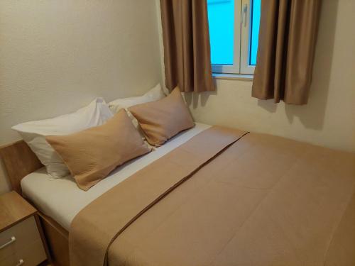a bed with pillows and a window in a room at Royal Apartments in Neum