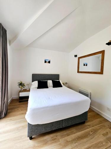 une chambre avec un grand lit blanc et un miroir dans l'établissement Très bel appartement T3 dans résidence hotellière 