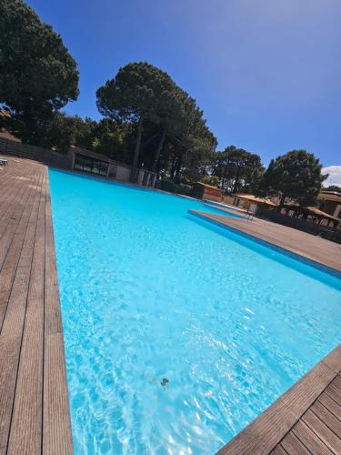 une grande piscine bleue avec une terrasse en bois dans l'établissement Très bel appartement T3 dans résidence hotellière 