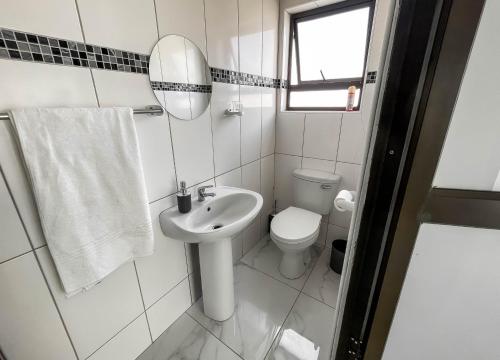 a white bathroom with a sink and a toilet at Onamungundo Backpackers in Walvis Bay