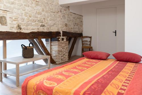 1 dormitorio con cama y pared de piedra en LES PORTES DE CASTELNAU, en Castelnau-de-Montmiral