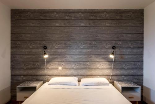 a bedroom with a bed with two lamps and a wooden wall at Le Charmagit in La Roche-sur-Foron