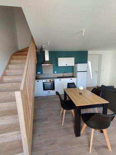 une cuisine et une salle à manger avec une table et un escalier dans l'établissement Gîte des Trois Cantons, à Beaurepaire