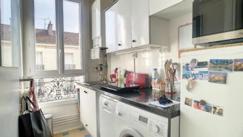 une cuisine avec lave-linge et sèche-linge ainsi qu'une fenêtre dans l'établissement Appartement typiquement parisien au pied du métro, à Issy-les-Moulineaux