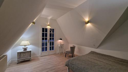 a bedroom with a bed and a chair and a window at Maison calme avec Spa et beau paysage, à 40mn des plages in Saint-Jean-de-Livet