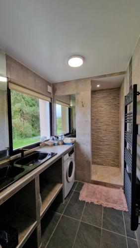 une salle de bain avec un lavabo et une machine à laver dans l'établissement Maison calme avec Spa et beau paysage, à 40mn des plages, à Saint-Jean-de-Livet