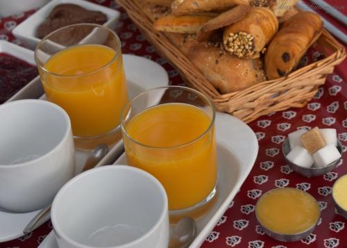 einen Tisch mit zwei Gläsern Orangensaft und einem Korb Brot in der Unterkunft MAS MLS in Saintes-Maries-de-la-Mer