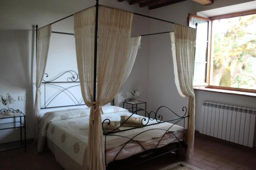 a bedroom with a canopy bed and a window at Agriturismo La Quercia in Boccheggiano