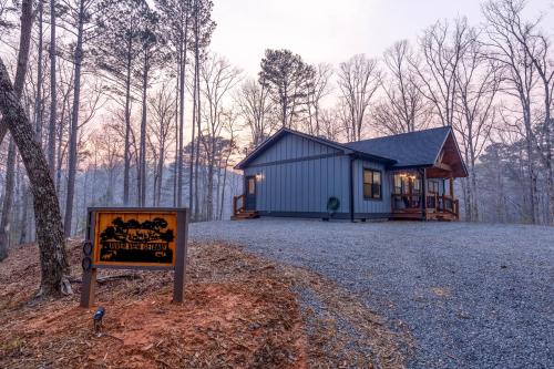 a small cabin in the woods with a sign in front of it at River View Getaway by 2DC in Ellijay