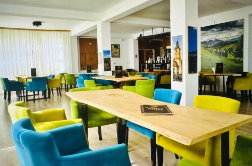 une salle à manger avec des tables, des chaises et des chaises jaunes et bleues dans l'établissement Casa Verde Poiana Brasov, à Poiana Brasov