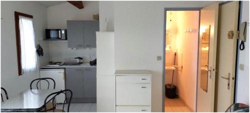 une cuisine blanche avec une table et des chaises dans l'établissement VALRAS - Studio avec parking fermé 50m de la plage, à Valras-Plage