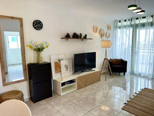 sala de estar con TV en una pared blanca en Las Olas DM cozy 2-bedrooms apartment en Maspalomas