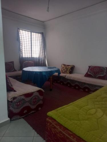 Cette chambre comprend 2 lits et une table. dans l'établissement résidence miftah sahile, à Zemmour Touirza