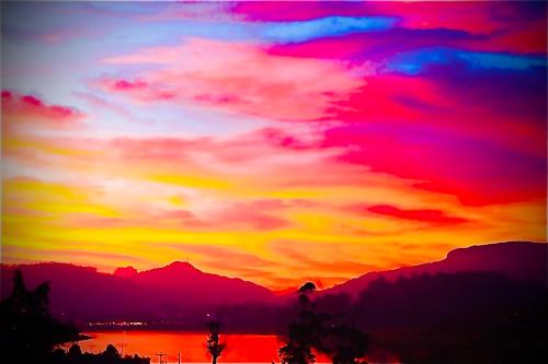 a sunset over a lake with a colorful sky at Serendipity Lake Artistic Bungalow by Heidis Home in Nuwara Eliya