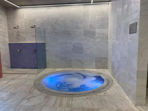 un bagno con doccia in vetro e vasca blu di Elysia park rose apartment a Paphos