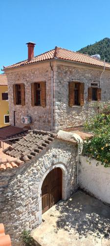 an old stone house with an arch in front of it at Dafnon Stone House in Leonidion