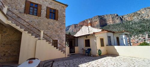 a building with a staircase next to a mountain at Dafnon Stone House in Leonidion