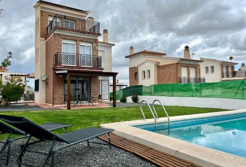 a house with a swimming pool and two chairs at Casa , Dílar, Granada con jardin y piscina in Dílar
