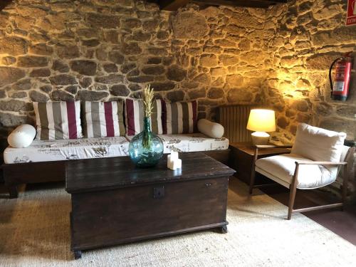 uma sala de estar com um sofá e uma mesa com um vaso em Hotel Rural Casal do Mouro em Ambroa