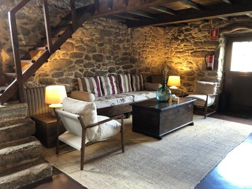 uma sala de estar com paredes de pedra, um sofá e cadeiras em Hotel Rural Casal do Mouro em Ambroa