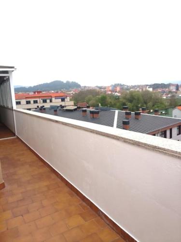 a white balcony with a view of a city at Ático en la Playa de Cangas in Cangas de Morrazo