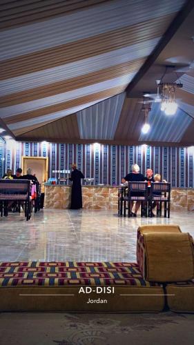 a room with people sitting at tables in a building at Mahmmad Luxury Camp in Disah