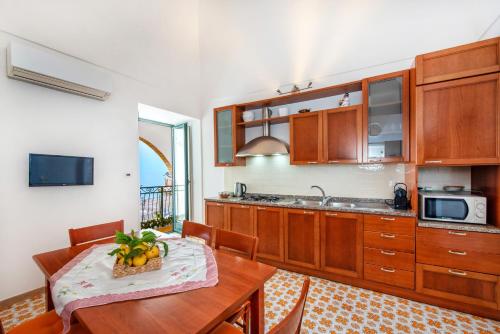 a kitchen with wooden cabinets and a table with a bowl of fruit at Casa Rosaria in Atrani