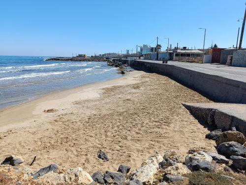 a beach with a retaining wall and the ocean w obiekcie Niros Beachfront Aparthotel w mieście Kokkini Hani