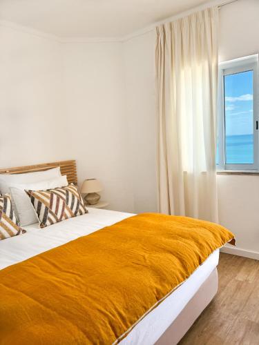 a bedroom with a large bed with a yellow blanket at Apartamentos Rossio Mar in Albufeira