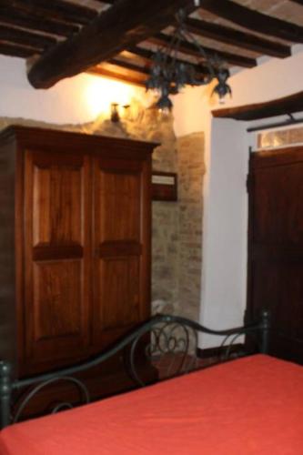 a bedroom with a red bed and a wooden cabinet at Appartamento borgo medioevale Rosa del Castello in Deruta