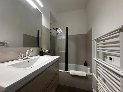 biała łazienka z umywalką i wanną w obiekcie La bulle FREBERMIS w mieście Villeneuve-sur-Lot