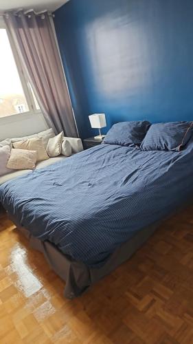 Ce lit se trouve dans une chambre dotée d'un mur bleu. dans l'établissement Vue sur la forêt, à Rambouillet