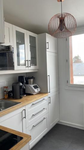 une cuisine avec des armoires blanches et un meuble lumineux dans l'établissement Vue sur la forêt, à Rambouillet