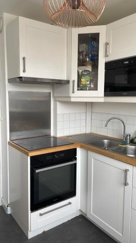 La cuisine est équipée de placards blancs et d'un four micro-ondes noir. dans l'établissement Vue sur la forêt, à Rambouillet