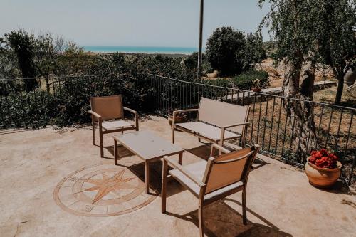 tres sillas y una mesa frente a una valla en Agriturismo Balcone Mediterraneo - Camere, en Ragusa