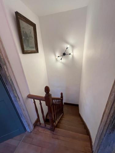 a hallway with a stairway with a clock on the wall at Appartement village in Simorre