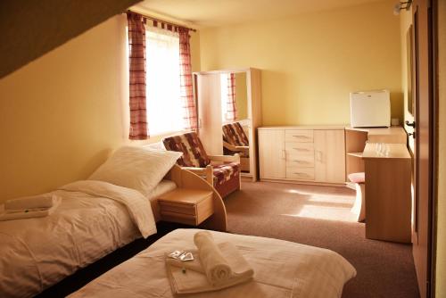 a hotel room with two beds and a chair at Penzion Na Pastoušce in Malšice