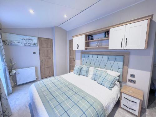 a bedroom with a large bed with blue and white at Lakeside Dorchester Lodge - Hot Tub with Fishing Peg in Tattershall