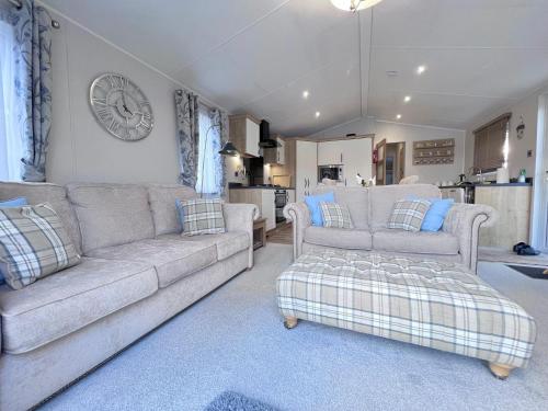 a living room with a couch and a clock on the wall at Lakeside Dorchester Lodge - Hot Tub with Fishing Peg in Tattershall