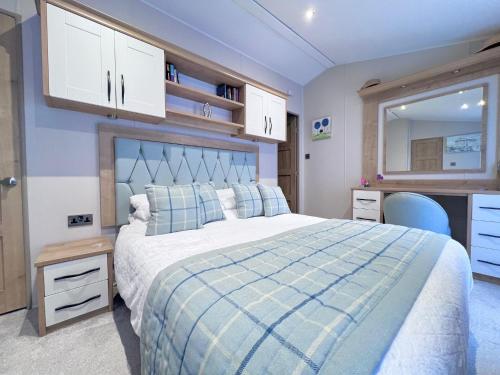 a bedroom with a large bed with a blue blanket at Lakeside Dorchester Lodge - Hot Tub with Fishing Peg in Tattershall