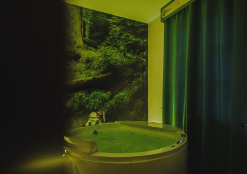 W łazience znajduje się wanna z zieloną zasłoną prysznicową. w obiekcie Borgo I Tre Baroni - Spa Suites & Resort w mieście Poppi