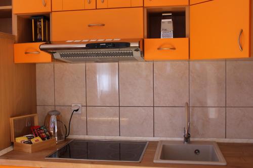 una cucina con armadi arancioni e lavandino di PARK Apartment a Bijeljina