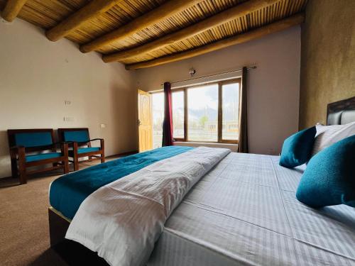 a bedroom with a large bed with a large window at HUNDER TAMARIX RESORT in Leh