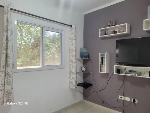 a living room with a television and a window at Apartamento prox Sesc Bertioga in Bertioga