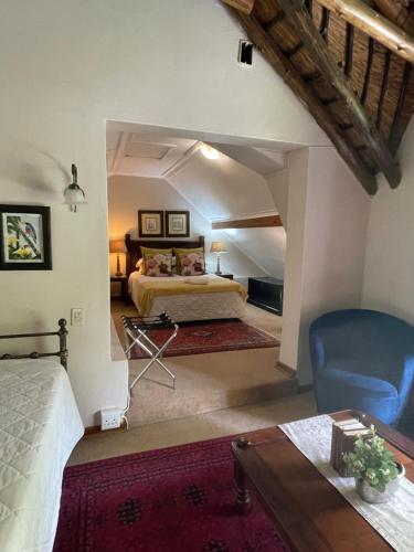 - une grande chambre avec un lit et une chaise bleue dans l'établissement De Witt'e Guest House, à Bloemfontein