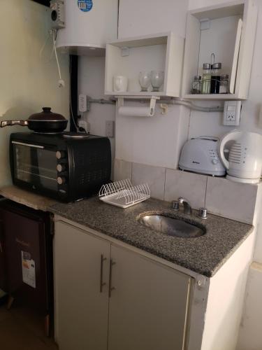 a kitchen counter with a sink and a microwave at Apartamento en Mendoza in La Cieneguita